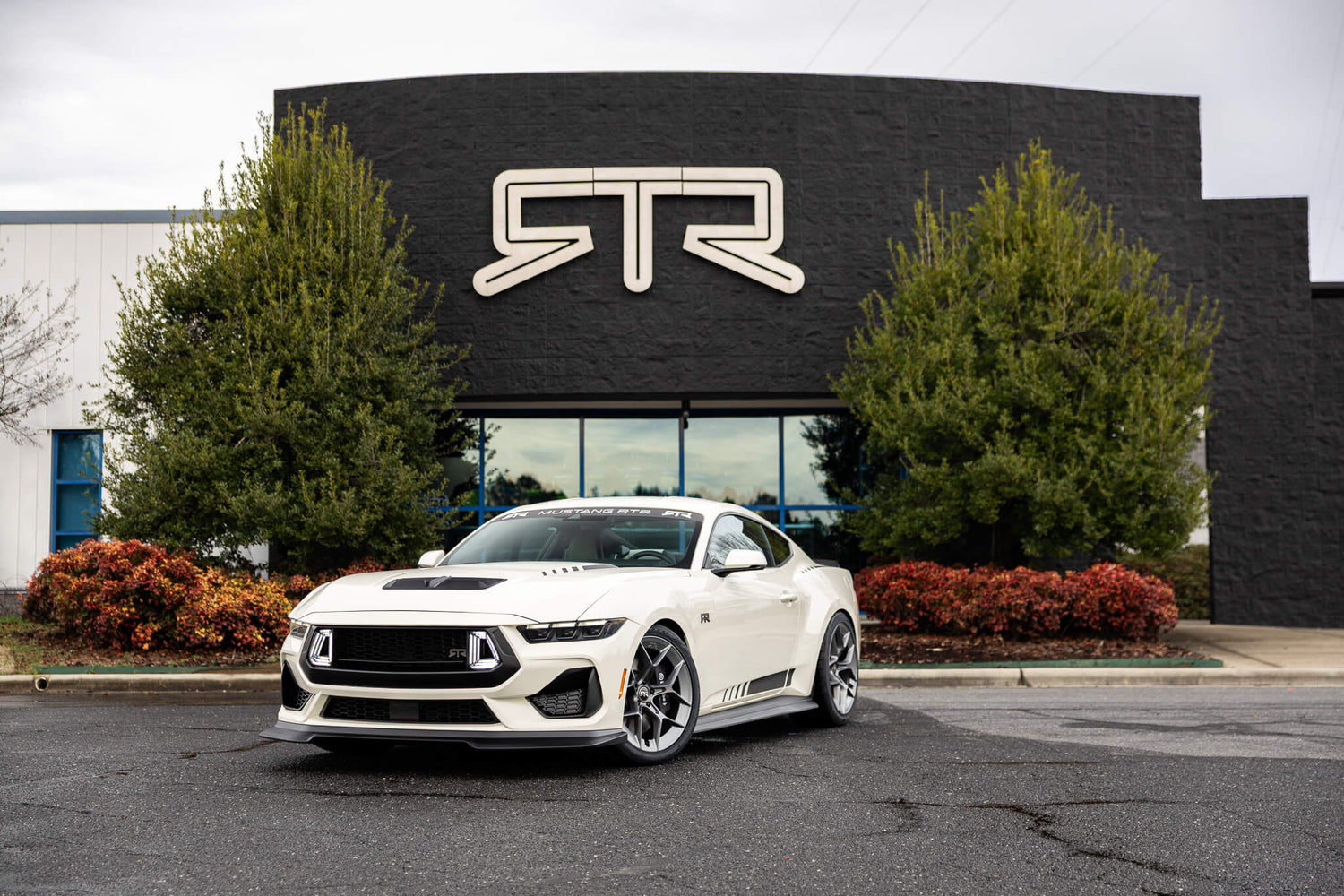 A 2025 Wimbledon white 60th anniversary Mustang RTR in front of the RTR Lab