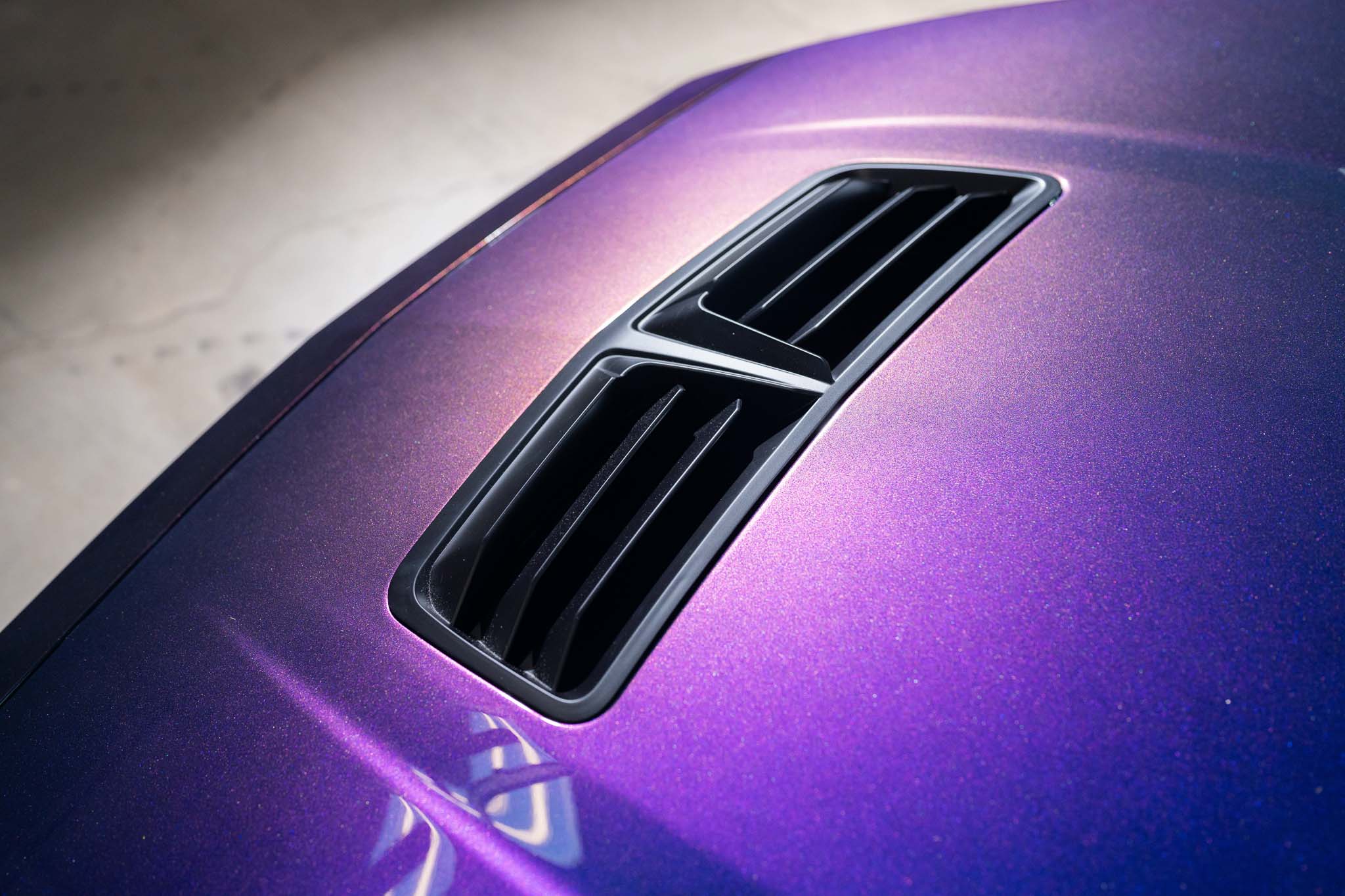 A close up of a Mystichrome Mustang RTR  hood with precise pigment layering to achieve the signature deep blues, purples, and greens that change under different lighting angles.