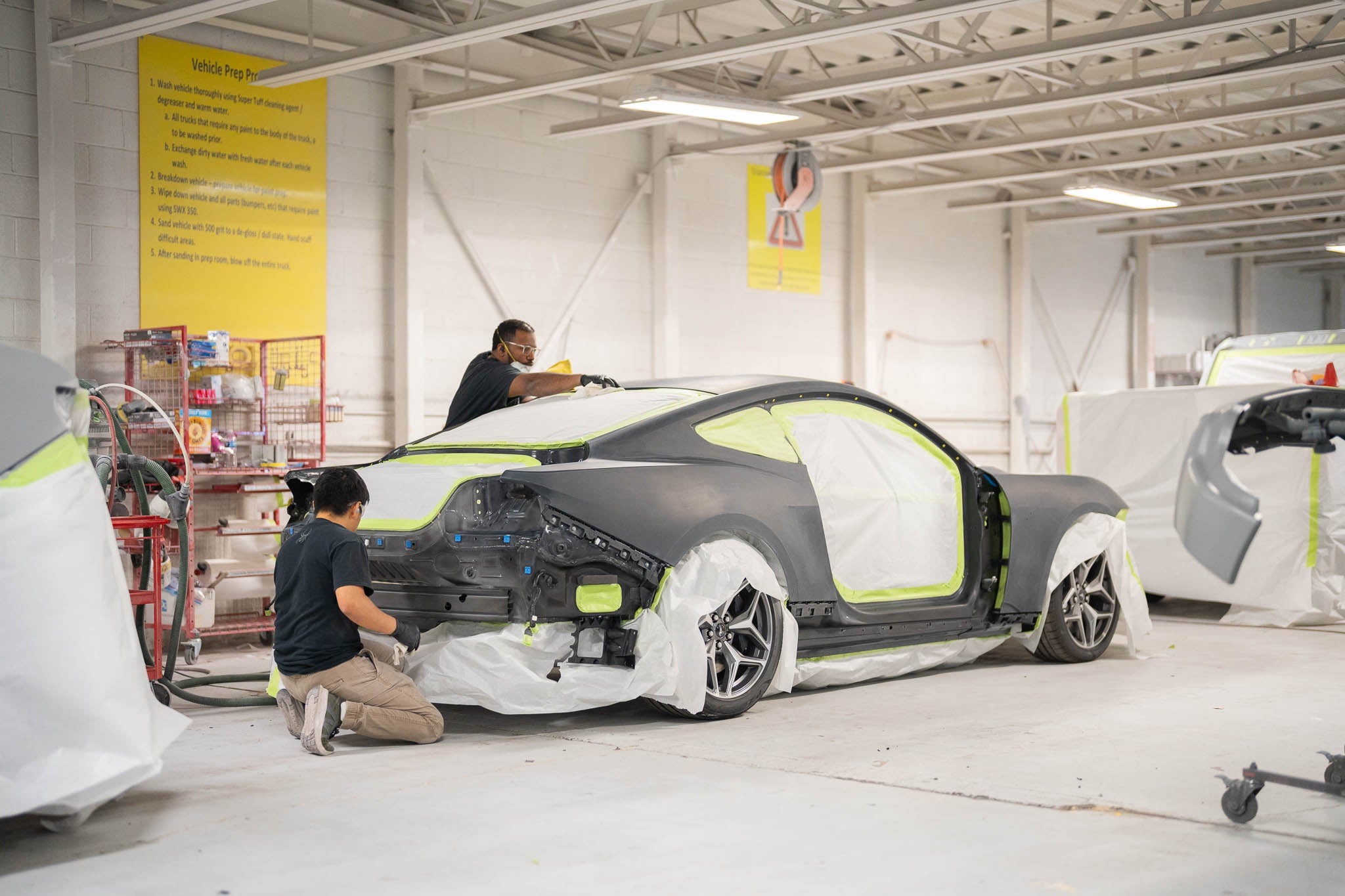 Two men working on a Mustang in a shop preparing for Mystichrome paint process