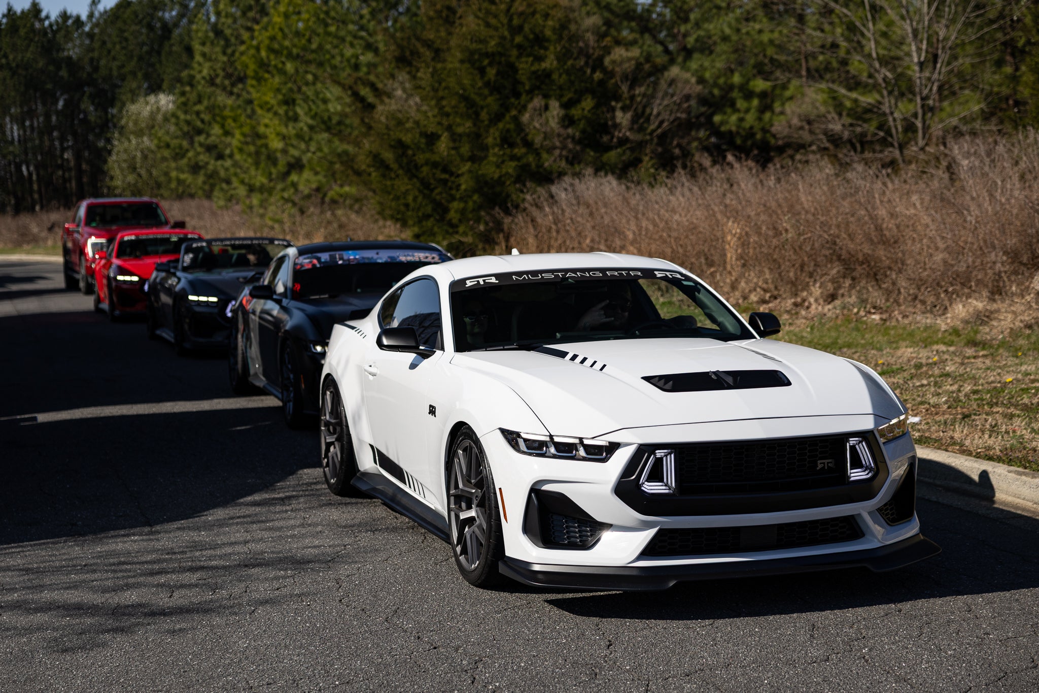 A group of Mustang RTR Spec 2 and Spec 3's driving on an asphalt road