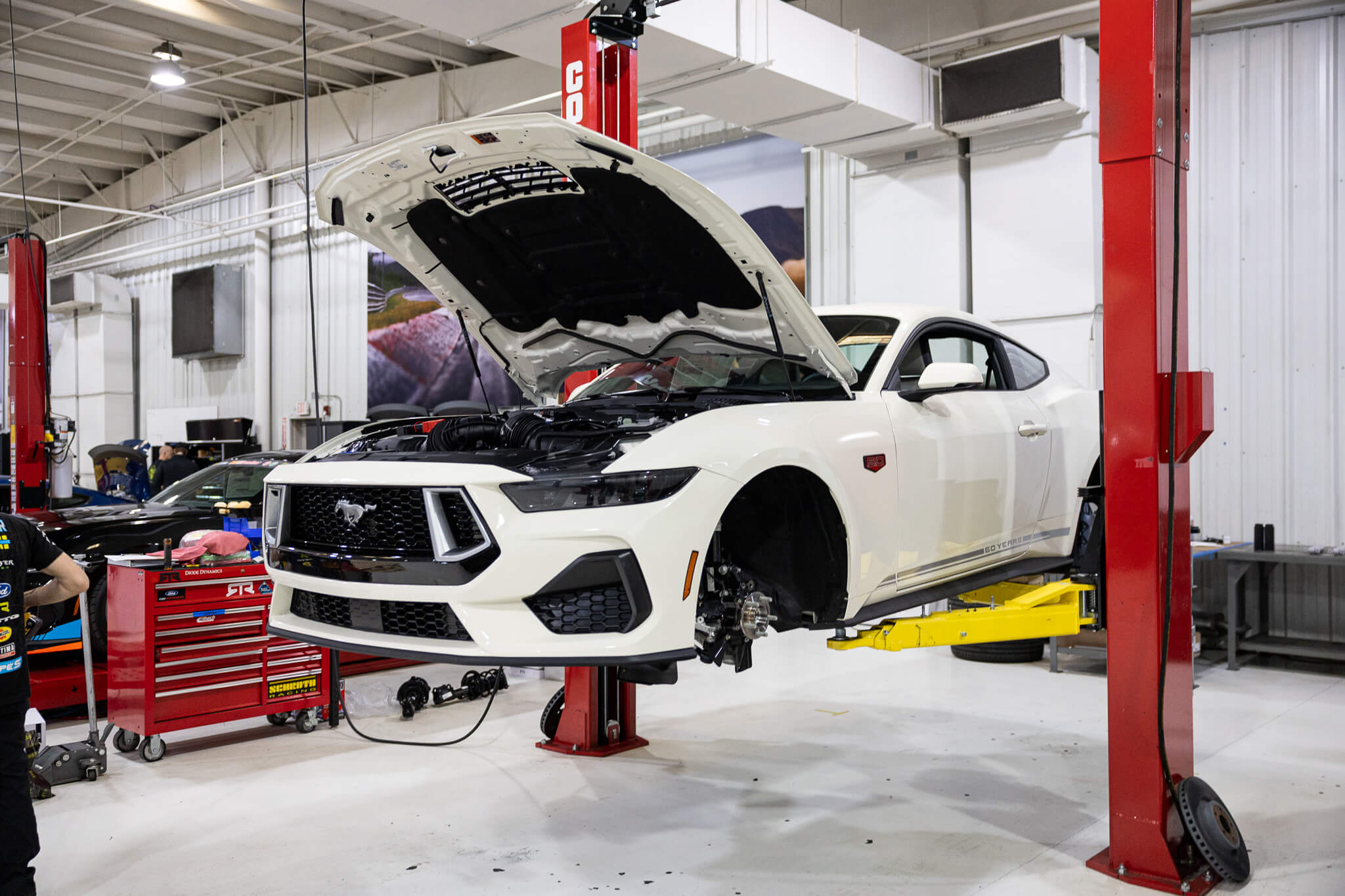 A Wimbledon white 60th anniversary Mustang on a car lift being built into a Mustang RTR