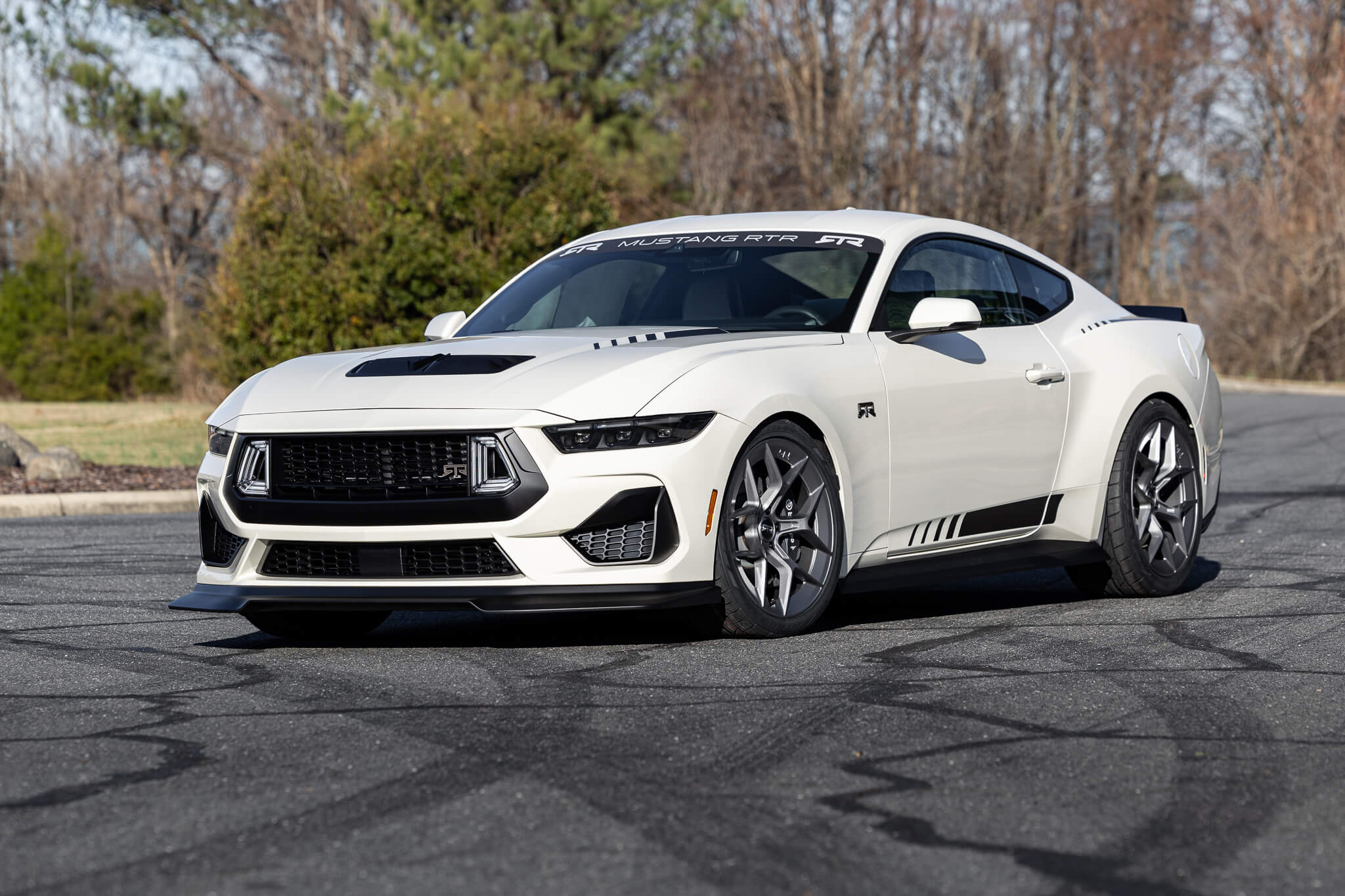 A 2025 Wimbledon white 60th anniversary Mustang RTR parked on an asphalt road