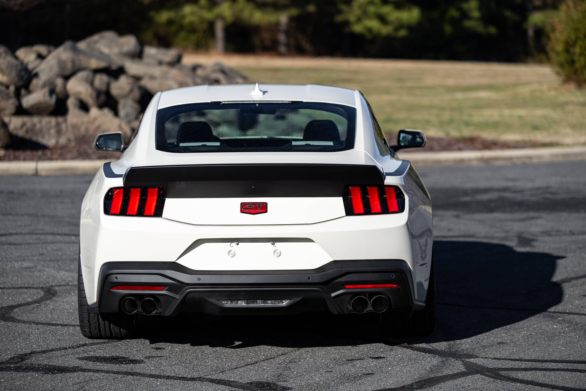 A 2025 Wimbledon white 60th anniversary Mustang RTR on an asphalt road with exclusive 60th Anniversary badges on trunk lid