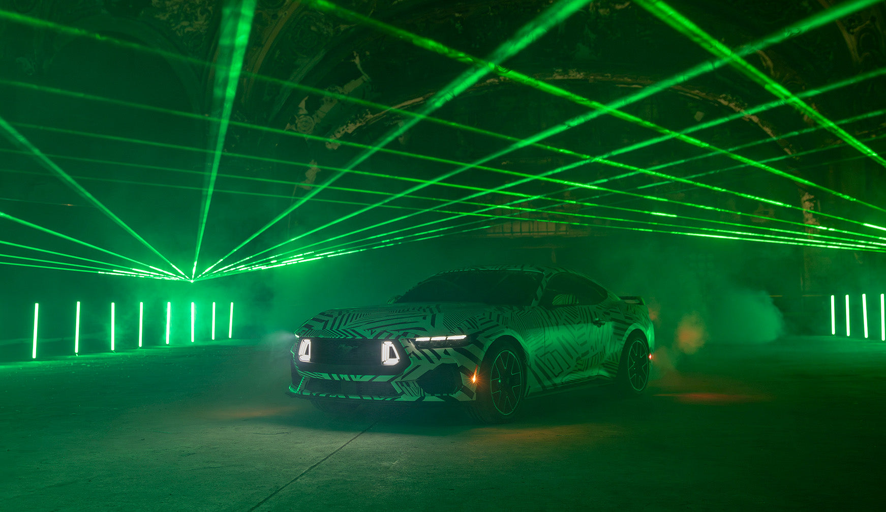 a front view of the Mustang RTR in dazzle camo in a historic building with green lasers overhead