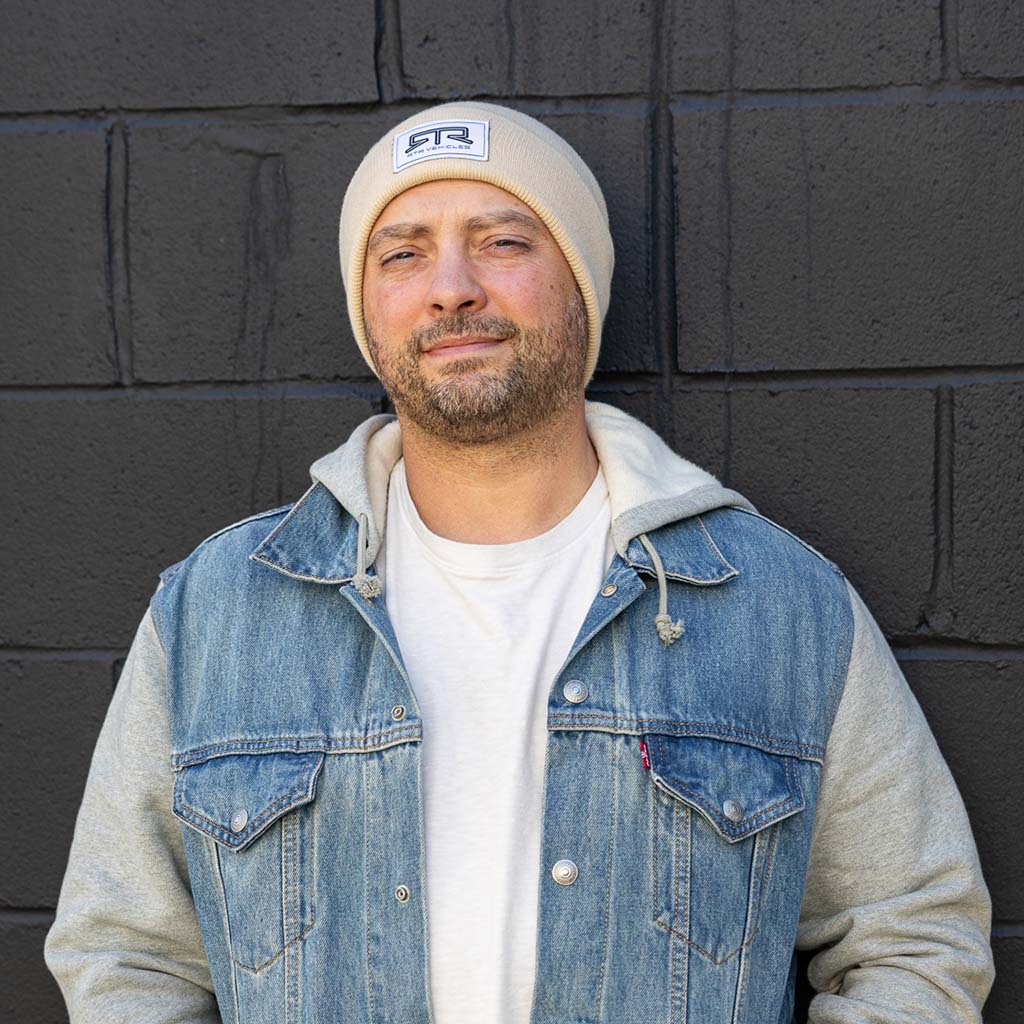 Man wearing a denim jacket and an RTR Beanie with a stitched logo, showcasing the beanie's snug fit and versatile style.